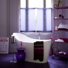 a bath tub sitting in the middle of a bathroom next to a shelf filled with towels