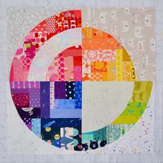 a quilted circle with many different colors and patterns on the fabric, as well as dots