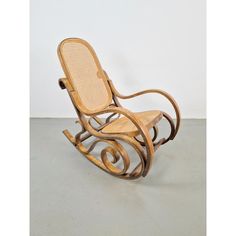 a wooden rocking chair sitting on top of a cement floor next to a white wall