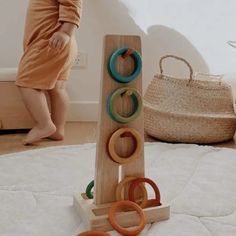 a baby standing next to a wooden toy with rings on it