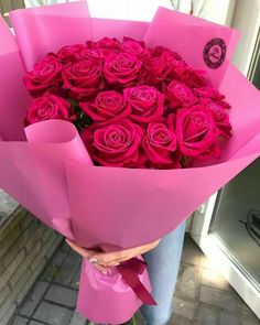 a person holding a large bouquet of pink roses in their hands and wrapped in pink paper