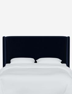 a black headboard with white sheets and pillows