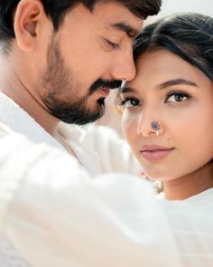 a man and woman with nose piercings on their forehead looking into each other's eyes