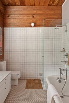 a bathroom with white tile and wood ceiling