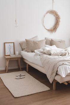 a bed with white sheets and pillows in a room next to a rug on the floor