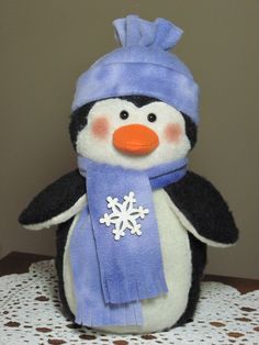 a stuffed penguin wearing a blue hat and scarf with a snowflake on it's head