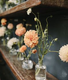 several vases filled with flowers sitting on top of a wooden shelf