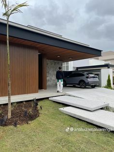 a car is parked in front of a house with a large driveway and grass area