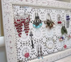 there is a white frame with many earrings on it