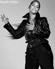 a black and white photo of a woman wearing a leather jacket with her hands in the air