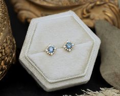 a pair of earrings sitting on top of a white box