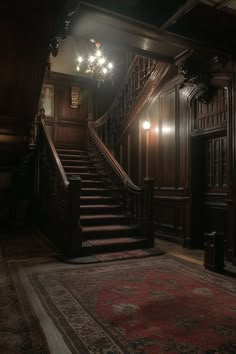 a staircase leading up to the second floor in a house with wood paneling and chandelier