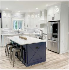 a kitchen with white cabinets and an island in the middle, surrounded by stools