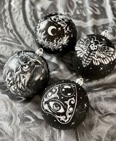 three black and white ornaments sitting on top of a silver cloth covered tablecloth,