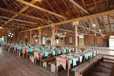 the inside of a barn with tables and chairs set up for a wedding or other function