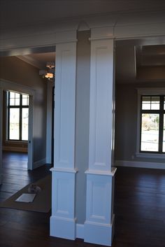 an empty living room with white columns and hard wood floors