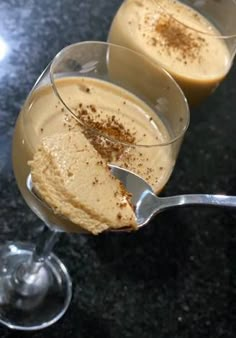 two glasses filled with dessert sitting on top of a black counter next to each other