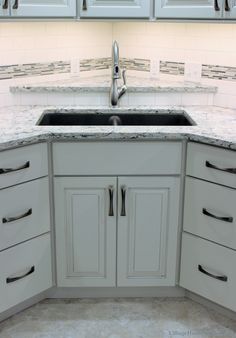 a kitchen with white cabinets and marble counter tops, along with an island style sink