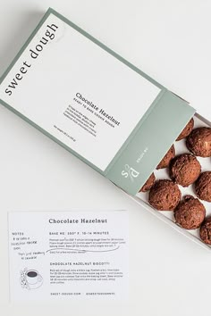 a box of chocolate truffles sitting on top of a white table next to an envelope