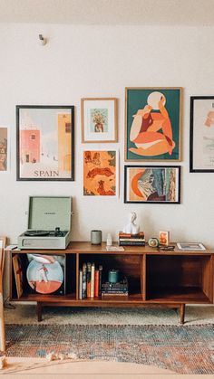 a living room with pictures on the wall and a laptop sitting on a coffee table