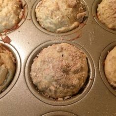 several muffins in a metal pan with some crumbs on the top