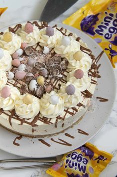 a cake with white frosting and chocolate toppings sitting on top of a table