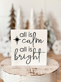 a wooden sign that says all is calm, all is bright on top of a table