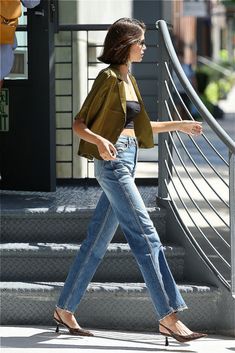 a woman walking down the street with her hand in her pocket and wearing high heels