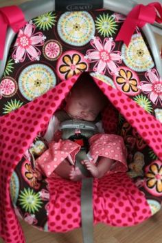 a baby in a car seat with pink and brown polka dots on the front cover