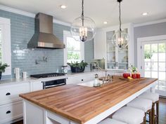 a kitchen island with stools in front of it and lights hanging from the ceiling