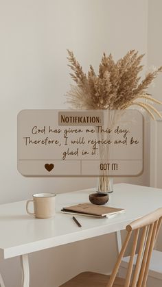 a white table topped with a vase filled with dry grass next to a wooden chair