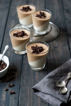 four glasses filled with chocolate pudding on top of a wooden table