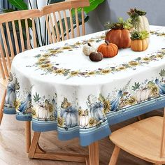 a table with pumpkins and gourds on it in front of a potted plant