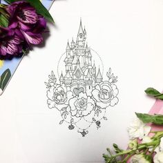 a drawing of a castle surrounded by flowers on a piece of paper next to purple and white flowers