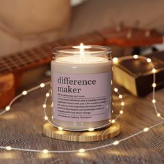 a lit candle sitting on top of a wooden table next to a string of lights