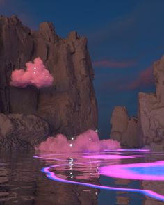 some pink clouds floating in the air over water with rocks and mountains behind them at night