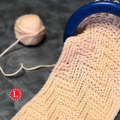 a knitted sock next to a ball of yarn and a crochet hook