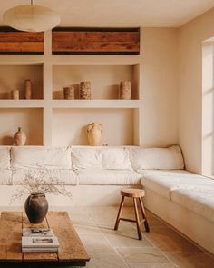 a living room filled with furniture and lots of shelves on the wall above it's coffee table