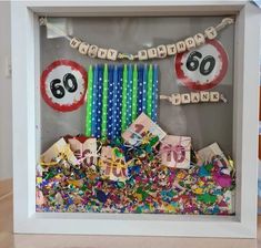 a birthday decoration with candles and streamers in a shadow box filled with confetti