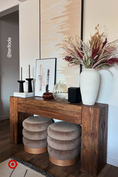 a wooden table topped with two stools and a vase filled with flowers