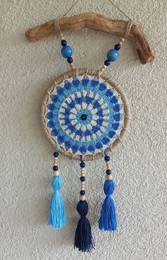 a blue and white beaded dream catcher hanging on a wall next to a branch