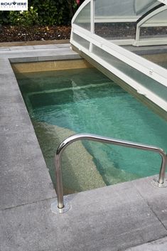 an empty swimming pool with steps leading up to the water's edge and windows above it