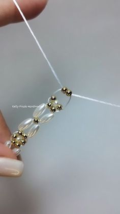 someone is stitching together beads on a piece of string with white and gold thread