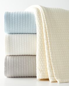 four folded towels stacked on top of each other in white, blue and grey colors