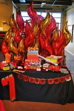 a table topped with lots of red and gold balloons next to a black table cloth