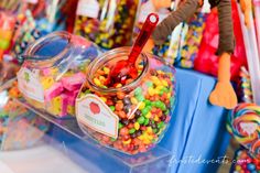 there are many candies on display in the glass containers with spoons next to them