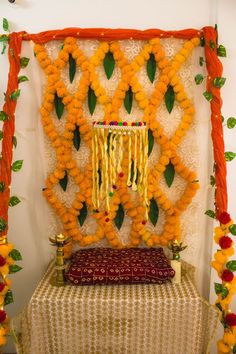 an arrangement of flowers and garlands on display in front of a white wall with orange trim