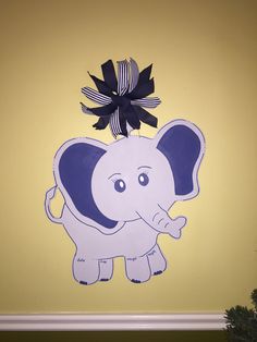 an elephant with a black bow on its head hanging from the side of a wall