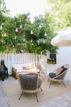 two wicker chairs sitting on top of a rug in front of a white fence