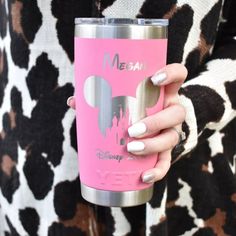 a woman holding a pink tumbler cup with mickey mouse ears on it's side